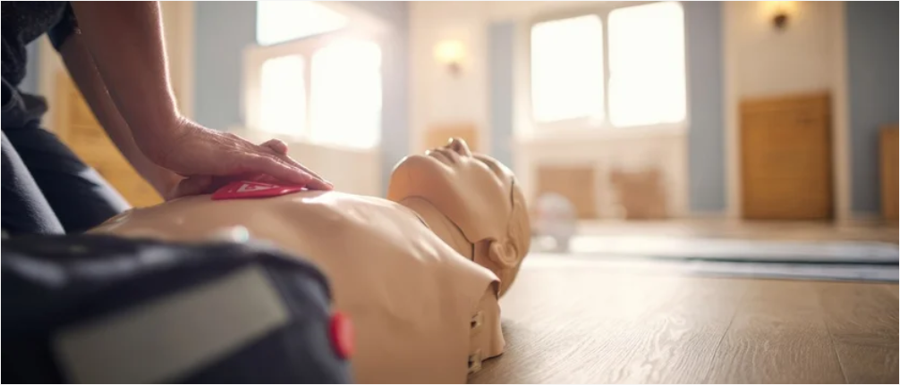 Instructor demonstrating CPR chest compressions on training mannequin during hands-on certification class